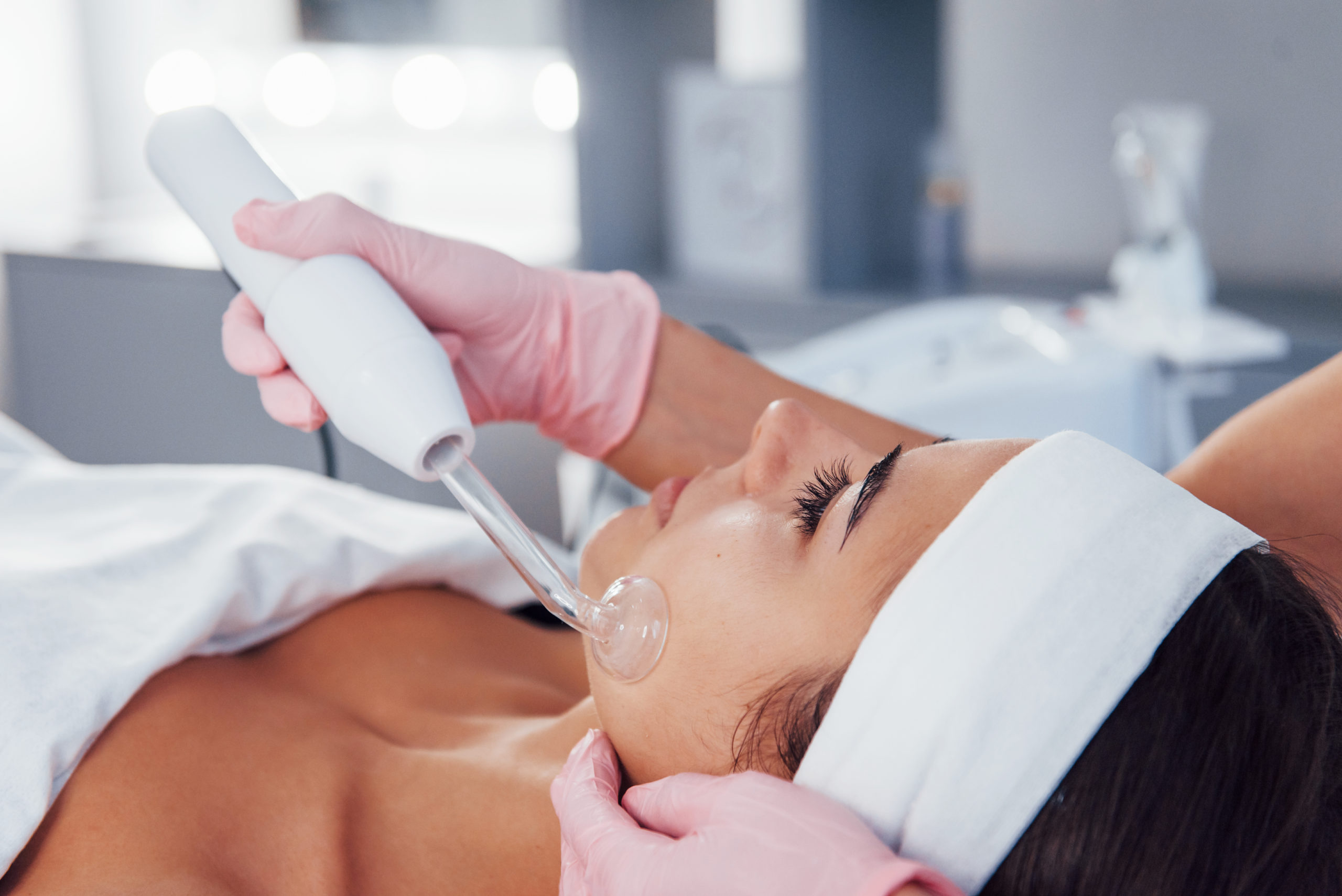 Close up view of woman that lying down in spa salon and have face cleaning procedure by using modern device